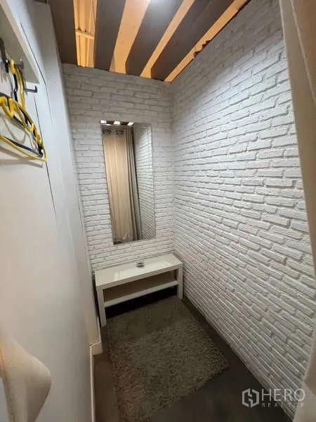 Retail Space for rent - Compact fitting or consultation room with white brick walls, a mirror, and a small table.