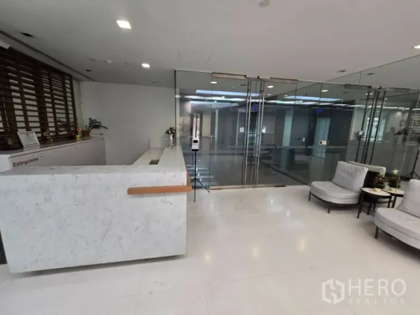Office Space for rent in Watthana, Bangkok - Reception area with white marble counter and lounge chairs facing glass entry.