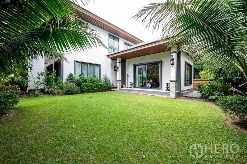 Detached House for sale in Prawet, Bangkok - Back garden with green lawn, covered terrace and wide sliding doors to the house.
