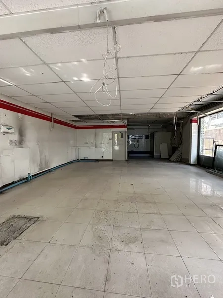 Retail Space for rent in Watthana, Bangkok - Empty retail unit interior with tiled floors, suspended ceiling and wide street‑facing windows in Phra Khanong, Bangkok.