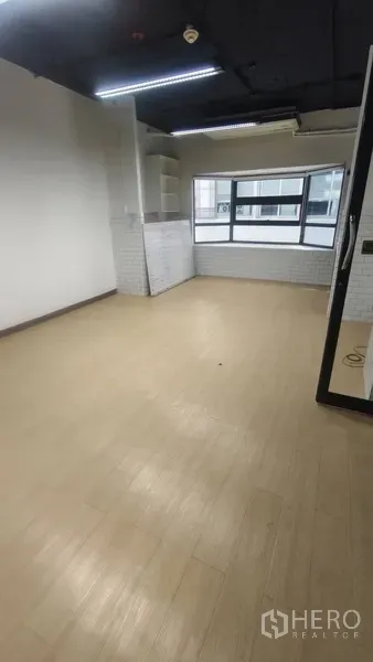 Office Space for rent in Pathum Wan, Bangkok - Bright workspace with light wood-look flooring, large window and built-in shelves.