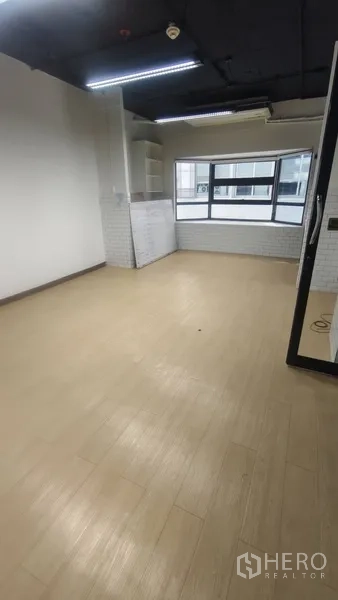 Office Space for rent in Pathum Wan, Bangkok - Bright workspace with light wood-look flooring, large window and built-in shelves.