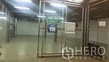Factory for sale in Lam Luk Ka, Pathum Thani - Secure caged storage area with chain-link fencing and overhead lighting inside the warehouse.