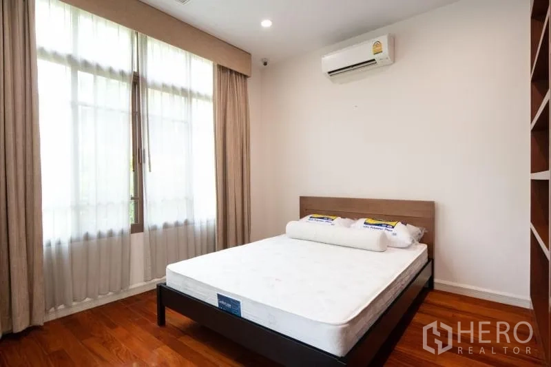 Detached House for rent in Watthana, Bangkok - Secondary bedroom with large window, curtains and wall-mounted air conditioner.