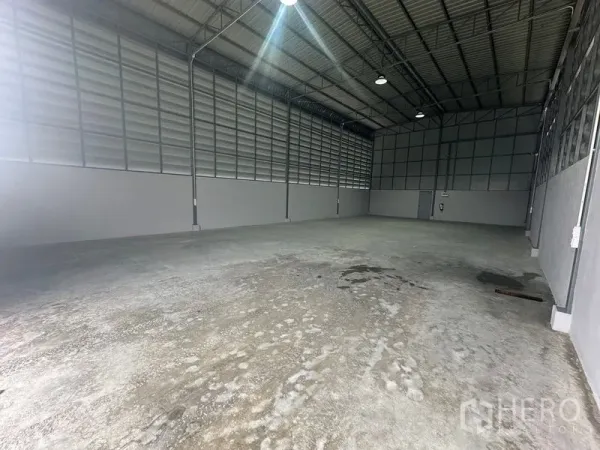 Warehouse for rent in Prawet, Bangkok - Spacious warehouse interior with high gable ceiling, steel trusses, louvered metal walls and concrete floor in Prawet, Bangkok.