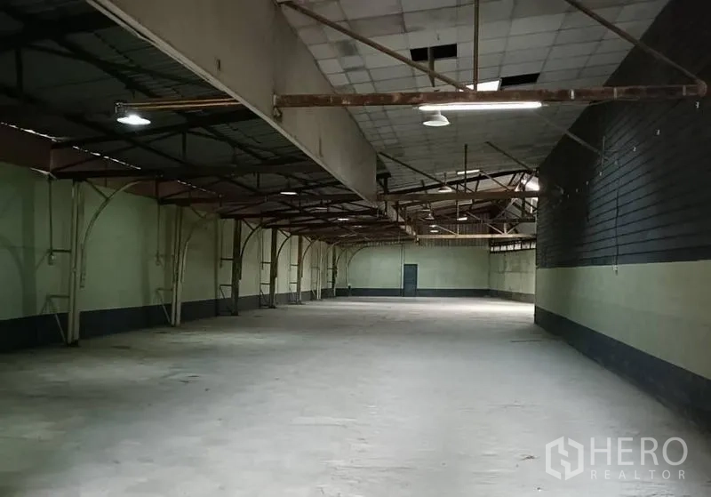 Warehouse for rent in Bang Khen, Bangkok - Deep open-plan warehouse with steel arches, suspended lights and side access door.