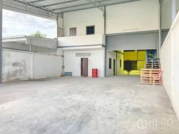 Factory for rent in Samut Prakan - Spacious covered forecourt with roller shutter door, office block and ample parking space.