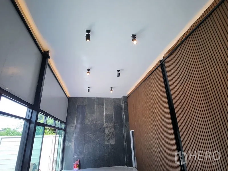 Warehouse for rent in Lam Luk Ka, Pathum Thani - Double-height lobby with spotlights, stone feature wall and wooden slats.