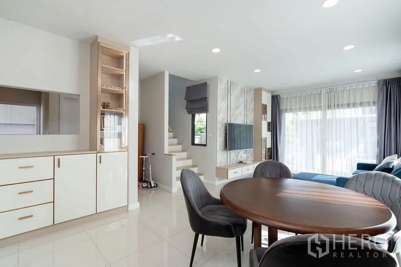 Detached House for rent in Bang Phli, Samut Prakan - Dining corner and stairway beside a marble TV wall in a bright open-plan space.