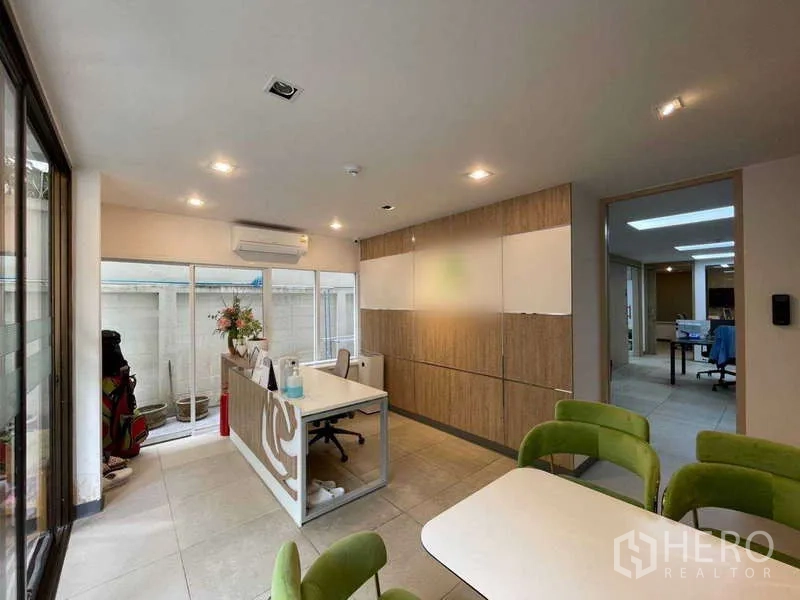 Home Office for rent in Watthana, Bangkok - Reception area with front desk, green chairs and wood cabinetry.