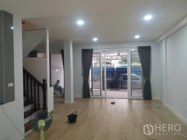Townhouse for rent in Khlong Toei, Bangkok - Bright open-plan living room with wood floors, recessed lights and sliding glass doors.