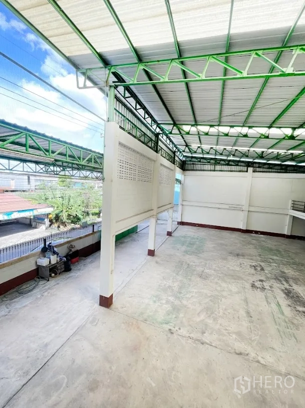 Warehouse for rent or sale in Thanyaburi, Pathum Thani - Side bay with translucent roofing and ventilation block walls along the perimeter fence.