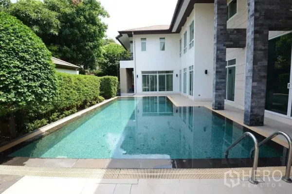 Detached House for sale in Bang Kapi, Bangkok - Private lap pool alongside a two-storey home bordered by hedge and stone pillars