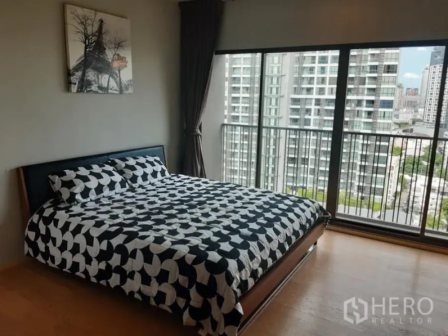 Condominium for rent in Bangkok - Bedroom corner with full-height windows and balcony railing overlooking the Sukhumvit skyline.