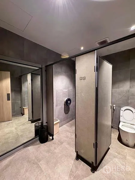 Warehouse for rent in Prawet, Bangkok - Clean restroom with partitioned cubicles, mirror, and toilet.