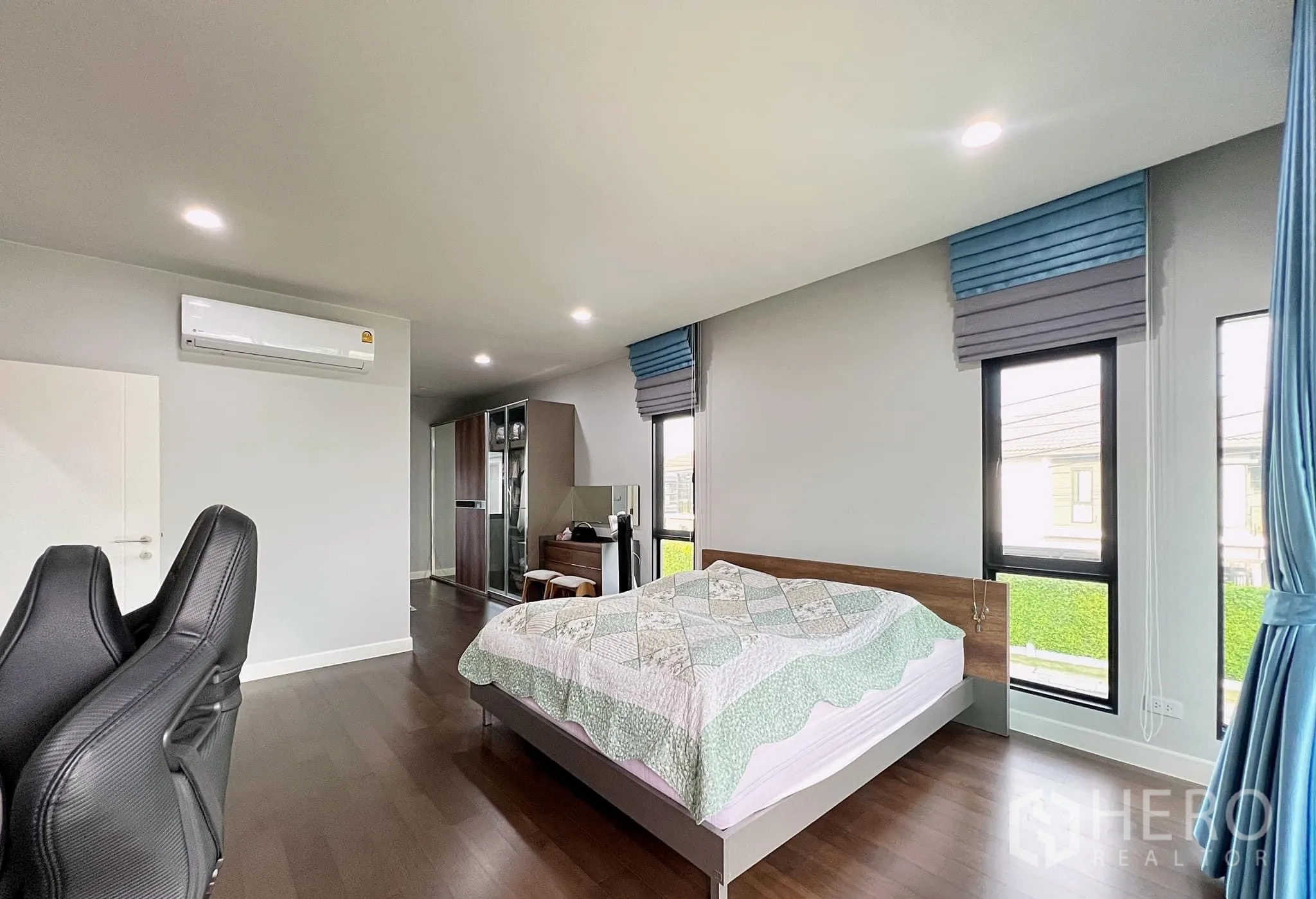 Detached House for rent or sale in Lam Luk Ka, Pathum Thani - Large master bedroom with wood floors, corner windows and bed.