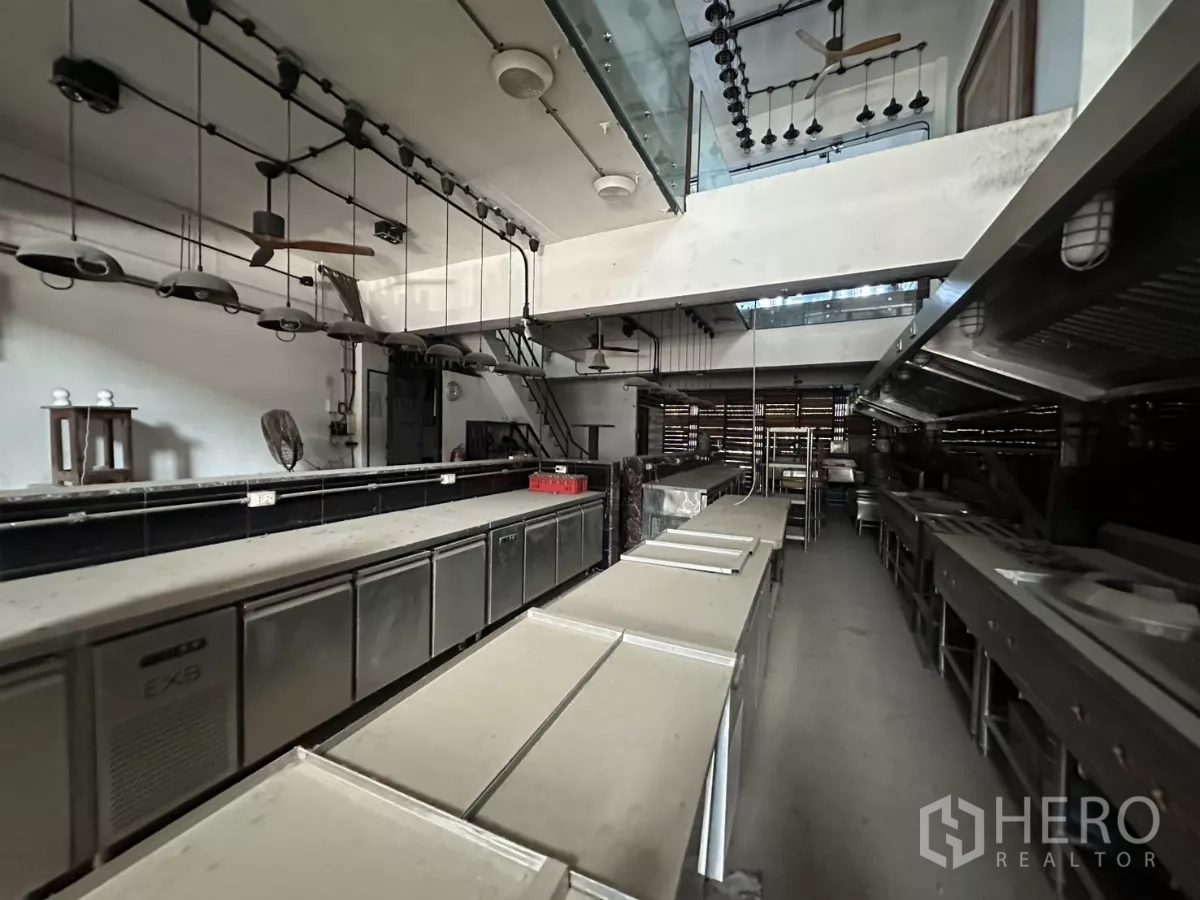Shophouse for rent in Bang Na, Bangkok - Open‑plan kitchen area with suspended lights, prep islands and full ventilation hoods.