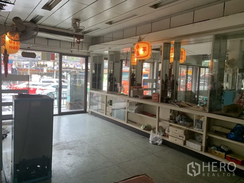 Shophouse for rent in Khlong Toei, Bangkok - Open showroom area with sliding glass doors and built-in glass display cabinets, street view outside.