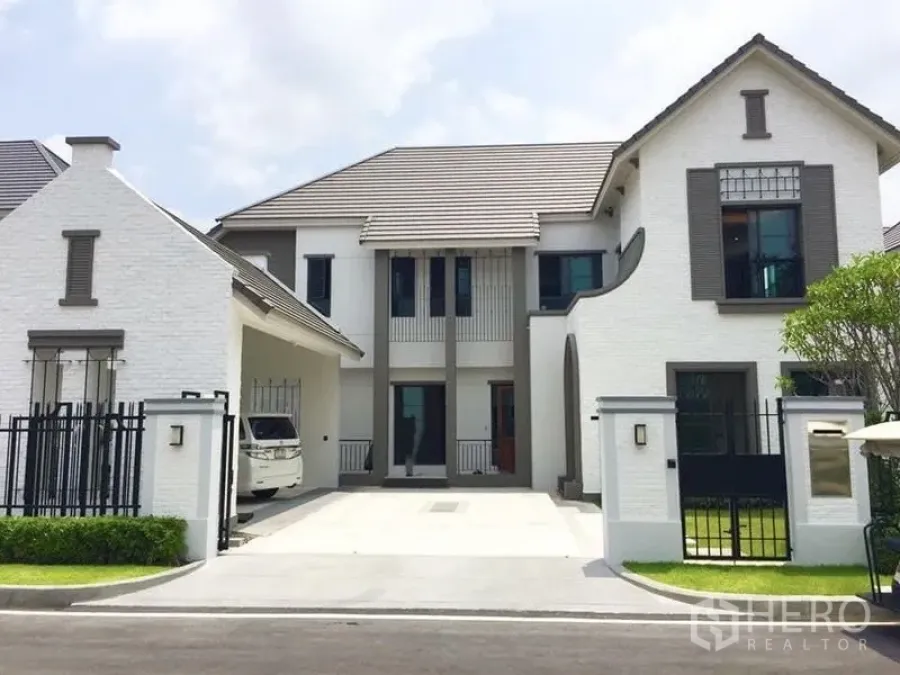 Detached House for sale in Mueang Samut Prakan, Samut Prakan - Front facade of a large detached home with carport and secure black metal gate.