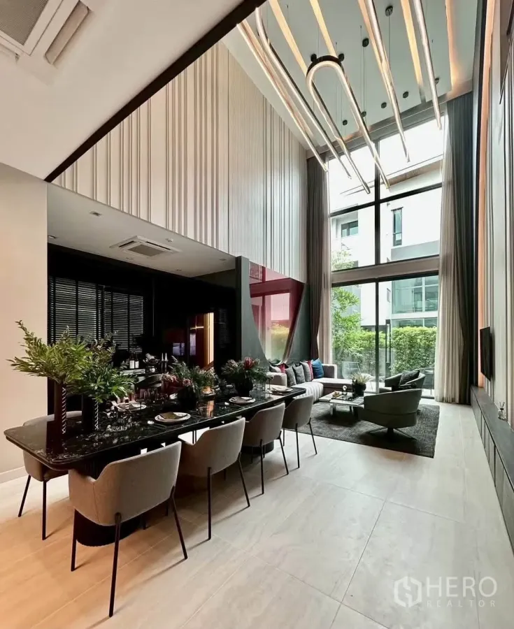 独栋房屋 for rent or sale in Suan Luang, Bangkok - 餐区设长形黑色餐桌、八把餐椅、落地窗与现代灯饰。