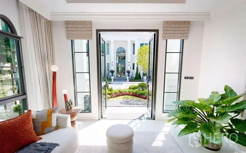 Detached House for rent in Bang Phli, Samut Prakan - Garden-facing lounge opening to a courtyard through French doors with abundant natural light and plants.