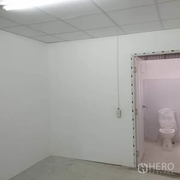 Warehouse for rent in Khlong Toei, Bangkok - White office room with drop ceiling and doorway leading to restroom.