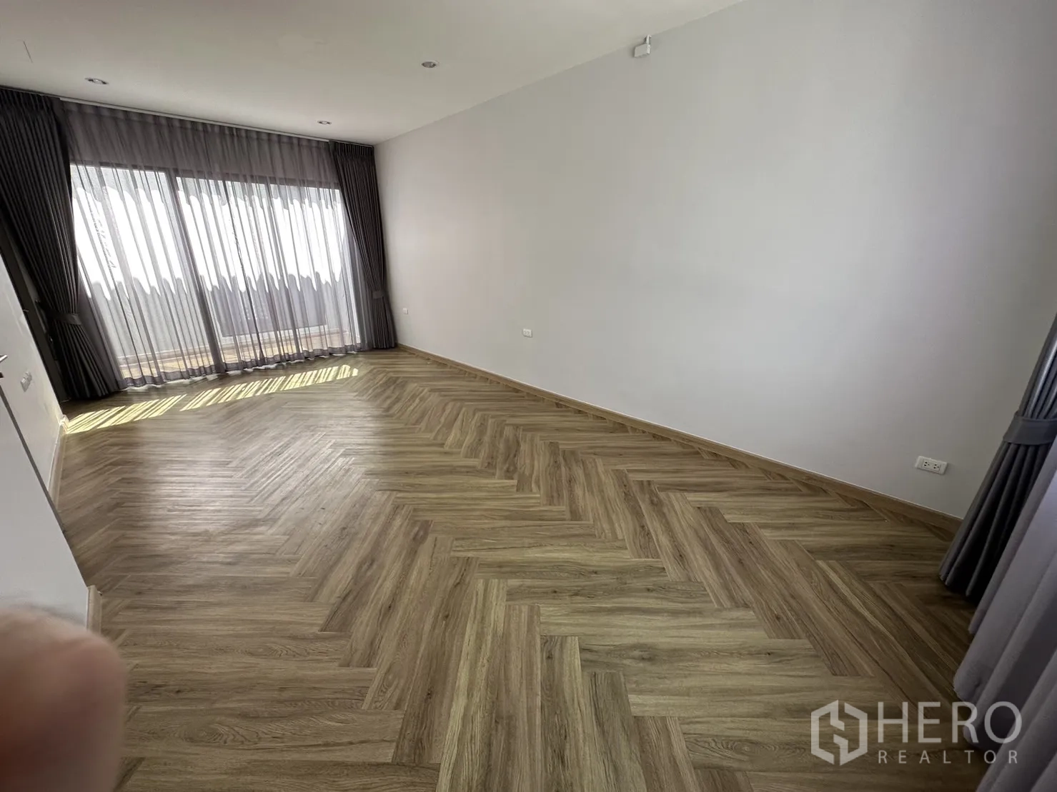 Home Office for rent or sale in Suan Luang, Bangkok - Large bedroom with herringbone wood floor and sliding glass doors to a balcony.