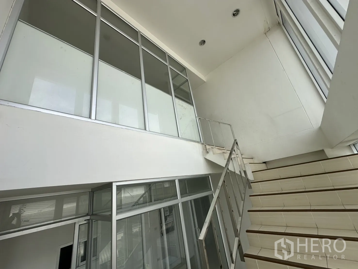 Factory for rent - Upward view of staircase and glass partitions in the office building.