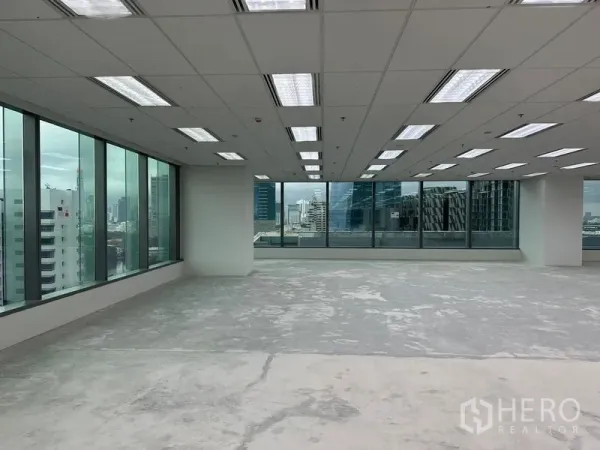 Office Space for rent in Ratchathewi, Bangkok - Office area with wraparound windows, white columns, unfinished concrete floor and skyline outlook.