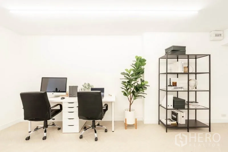Office Space for rent in Khlong Toei, Bangkok - Compact workspace with two white desks, black swivel chairs, potted plant and metal shelving against white walls.