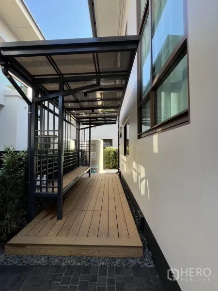 Detached House for rent or sale in Bang Kapi, Bangkok - Covered side terrace featuring a steel pergola over a raised wooden deck.