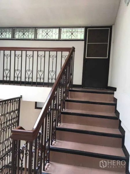 Townhouse for rent in Phra Khanong, Bangkok - Stairwell with decorative iron balustrade and high window panels.