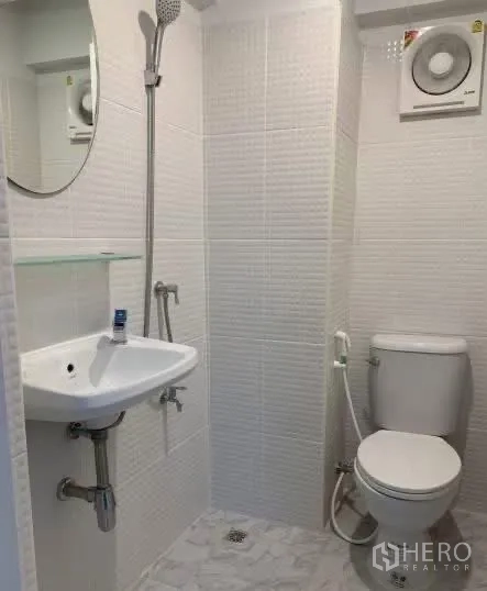 Home Office for rent in Sathon, Bangkok - Compact white-tiled bathroom with wall shower, sink, and toilet.