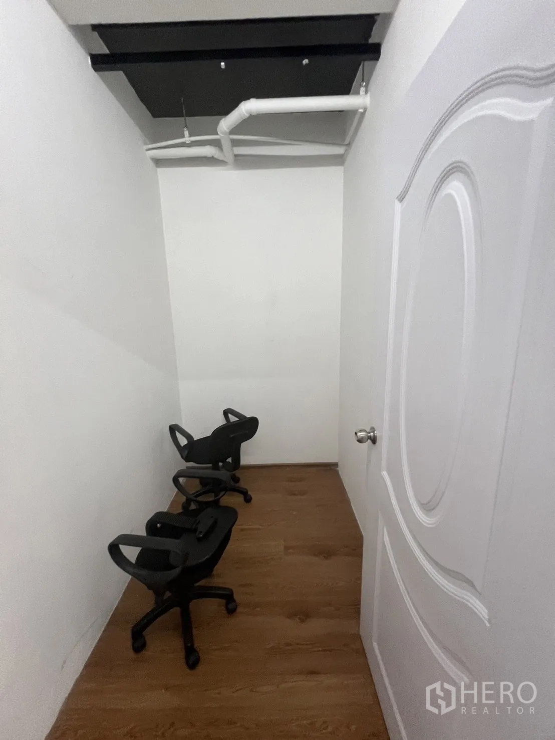 办公空间 出租在Khlong Toei, Bangkok - 狭长储物/机房，白墙、顶置管道与几把办公椅。
