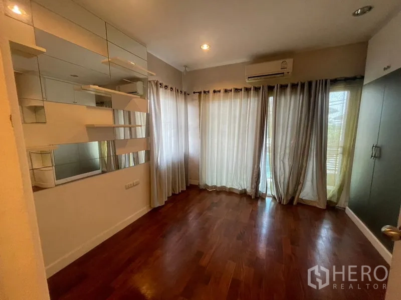 Detached House for rent or sale in Khan Na Yao, Bangkok - Corner bedroom with mirror shelving, floor-to-ceiling curtains and air conditioning.