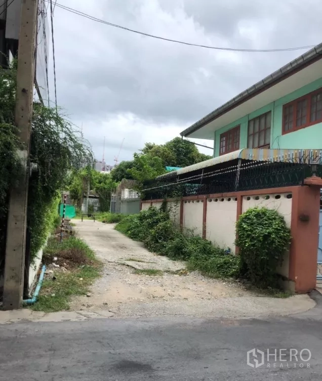 地 出售在Phra Khanong, Bangkok - 通往地块入口的住宅小巷，绿植与围墙林立。
