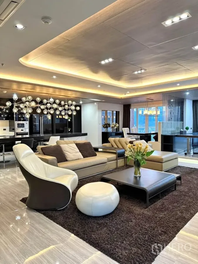 Condominium for rent or sale in Khlong Toei, Bangkok - Open-plan living room in a luxury Bangkok condo with sofa set, island kitchen and warm ceiling lighting.