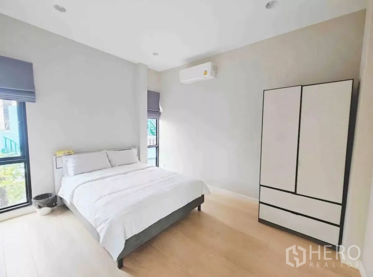 Detached House for rent in Phaya Thai, Bangkok - Simple guest bedroom with white bed, freestanding wardrobe and light wood floor.