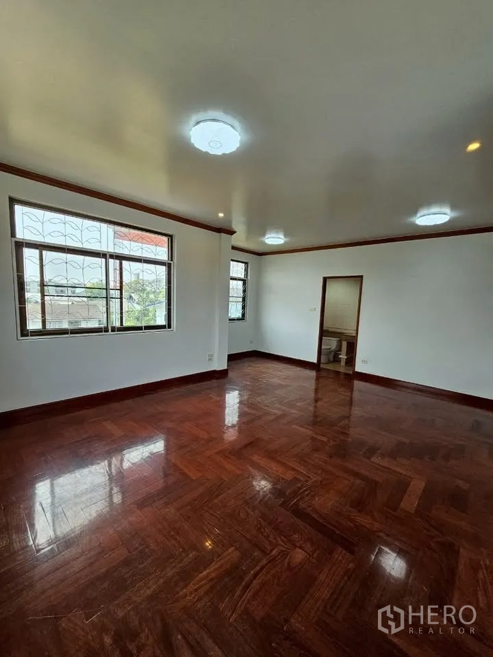 Home Office for rent in Wang Thonglang, Bangkok - Spacious bedroom with glossy parquet floor, windows with grilles and en‑suite door.