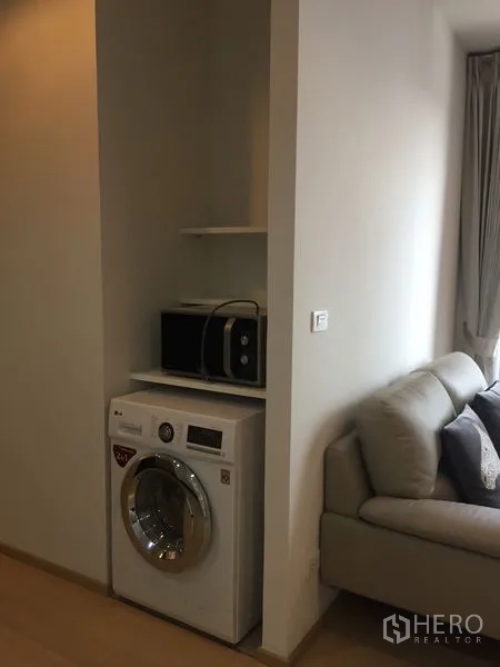 Condominium for rent in Watthana, Bangkok - In-unit laundry nook with front-load washer, microwave shelf and nearby sofa.