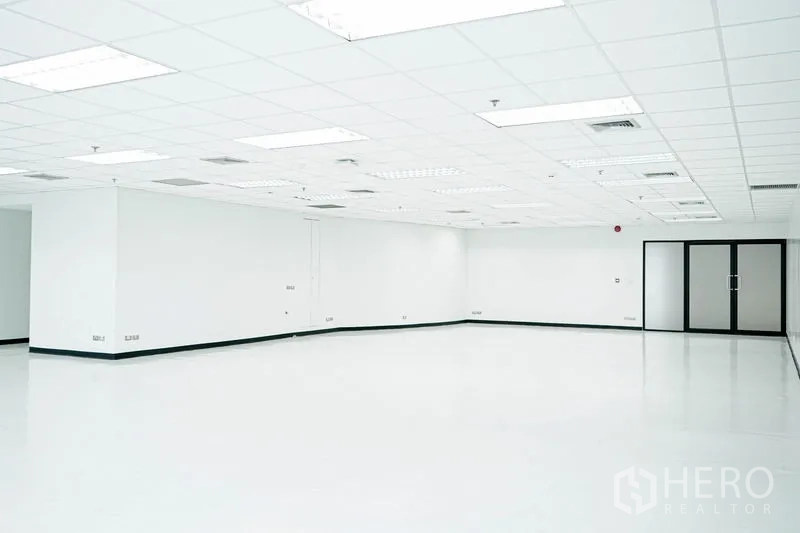 Office Space for rent in Watthana, Bangkok - Open office interior with ceiling air vents and a framed glass entry door.