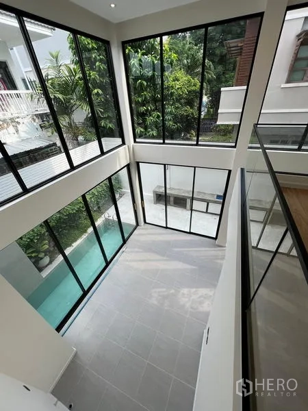 Home Office for sale in Phra Khanong, Bangkok - Aerial view of the double‑height space and lap pool through tall windows.