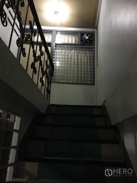 Shophouse for rent in Phra Khanong, Bangkok - Indoor staircase with metal railing leading to an upper floor and louvered window.