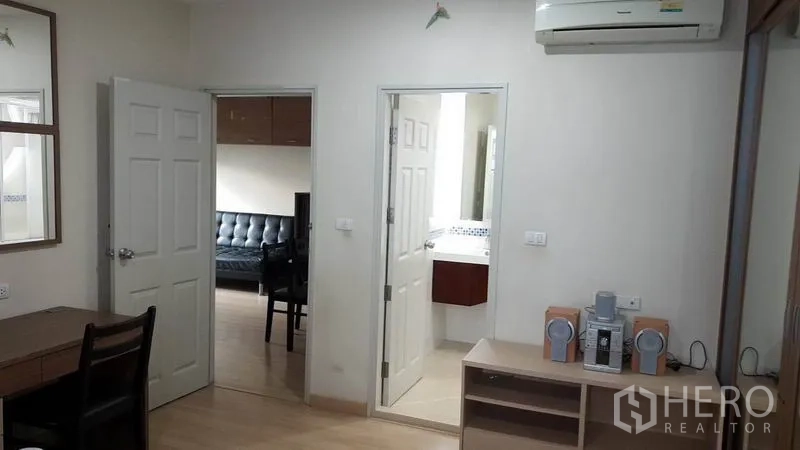 Condominium for rent in Bang Rak, Bangkok - Interior view showing doors to living room and bathroom, wall-mounted air conditioner, desk and shelving.