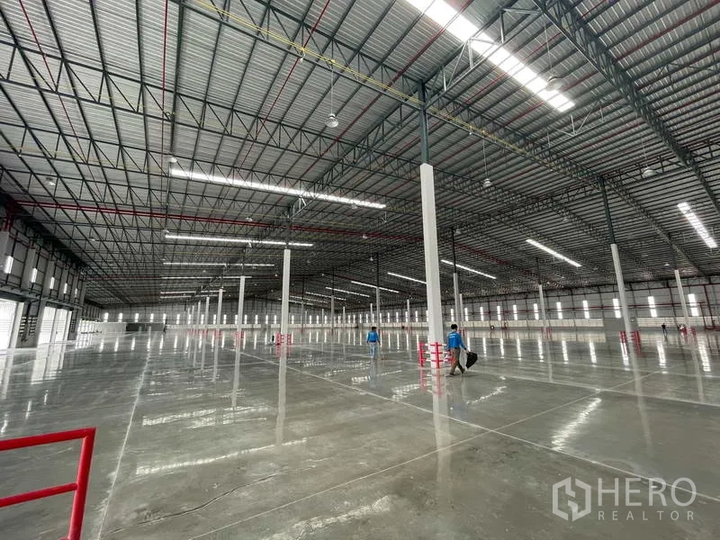 Factory for rent in Si Racha, Chon Buri - Expansive interior under steel roofing with reflective flooring and evenly spaced columns.