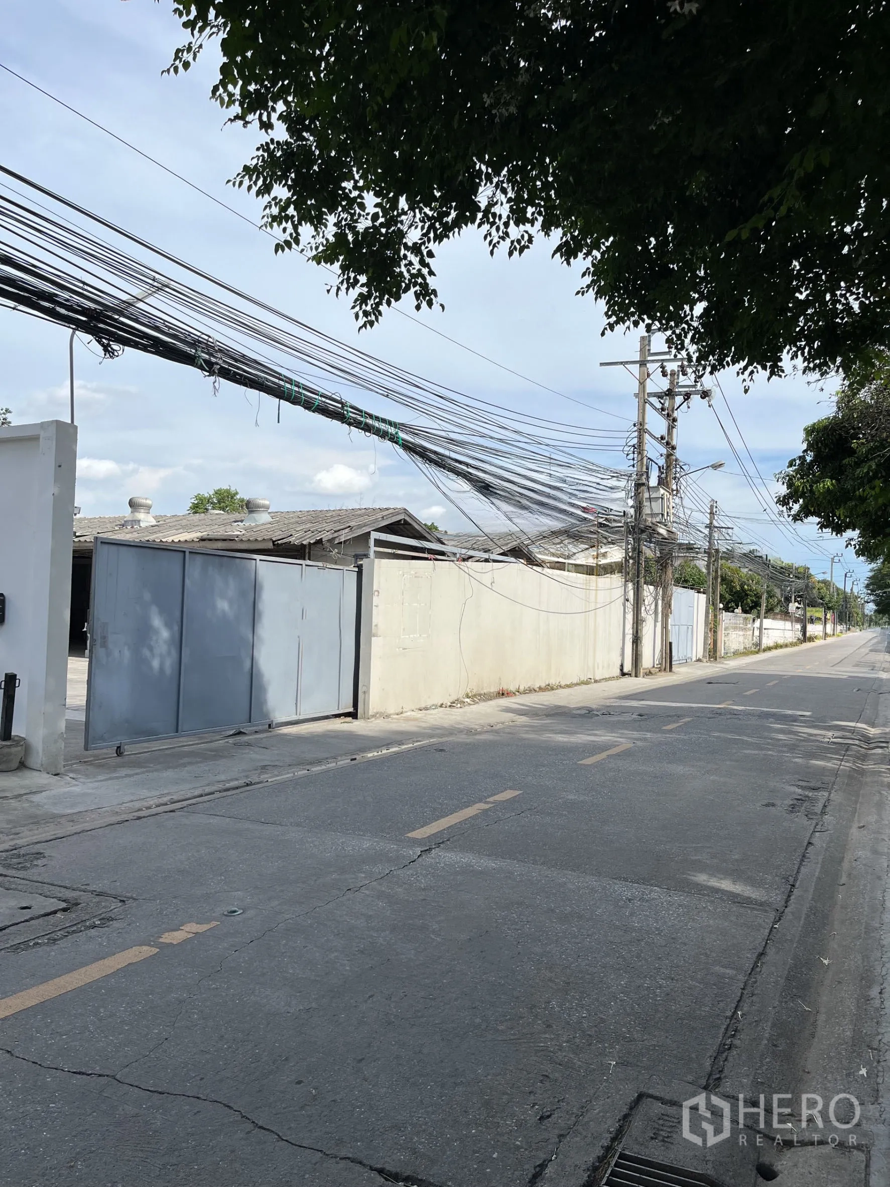 Warehouse for rent in Bangkok - Street view of gated warehouse entrance on a quiet local road.