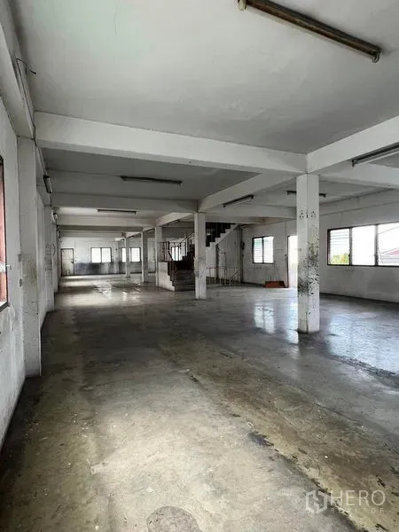 Factory for rent in Bang Na, Bangkok - Large open-plan production floor with concrete slab, columns and fluorescent lighting.