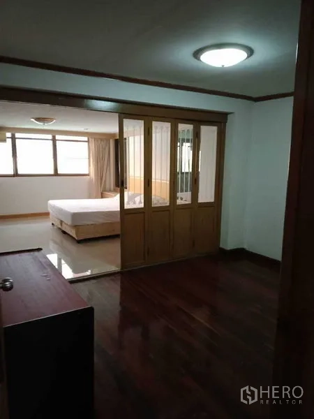 Townhouse for rent in Khlong Toei, Bangkok - Master suite with sliding glass-and-wood partition and wooden floors.