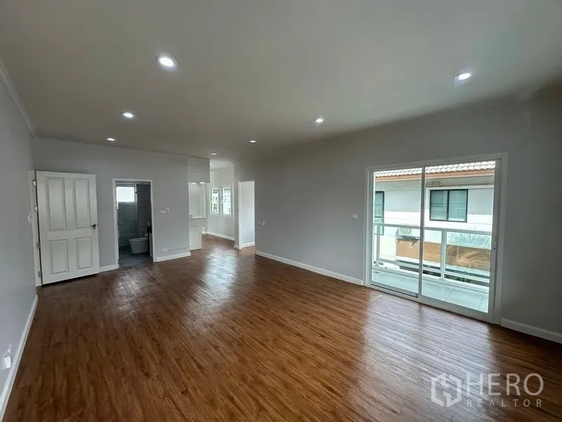 Detached House for sale in Lam Luk Ka, Pathum Thani - Upper-floor bedroom with wood floors, sliding door to balcony and ensuite access.