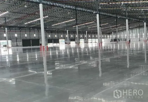 Factory for rent in Si Racha, Chon Buri - Warehouse interior showing multiple loading bays and a wide column grid on glossy concrete.
